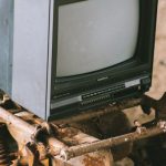 Screen Damage - Vintage television set on rusty vehicle on pathway