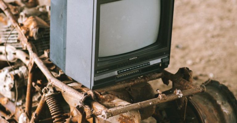 Screen Damage - Vintage television set on rusty vehicle on pathway