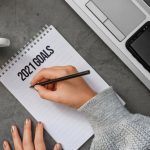 Resolution - Top view crop anonymous female in sweater writing down goals for 2021 year in notebook while sitting at desk with laptop and cup of coffee