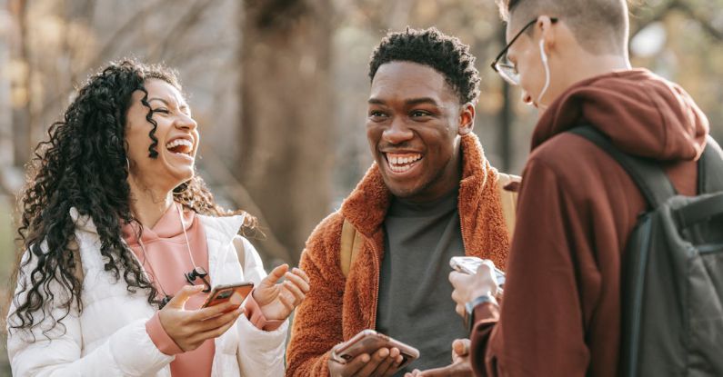 Smartphone Resolutions - Laughing diverse friends with smartphones in park
