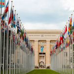 Resolution - From below of various flags on flagpoles located in green park in front of entrance to the UN headquarters in Geneva