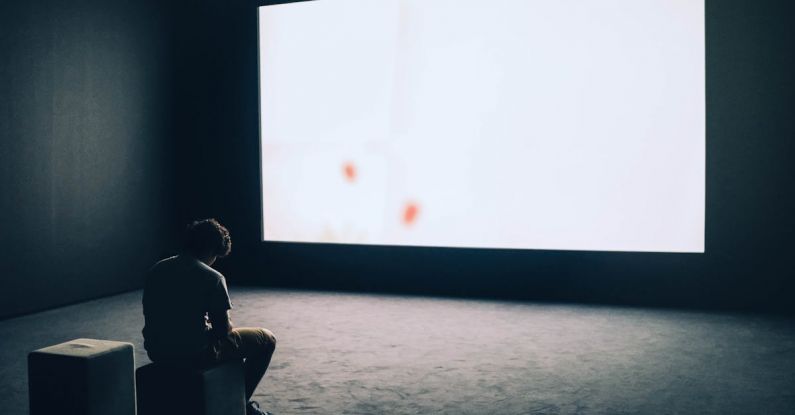 Projector Screen - Man Sitting in Front of Turned-on Screen